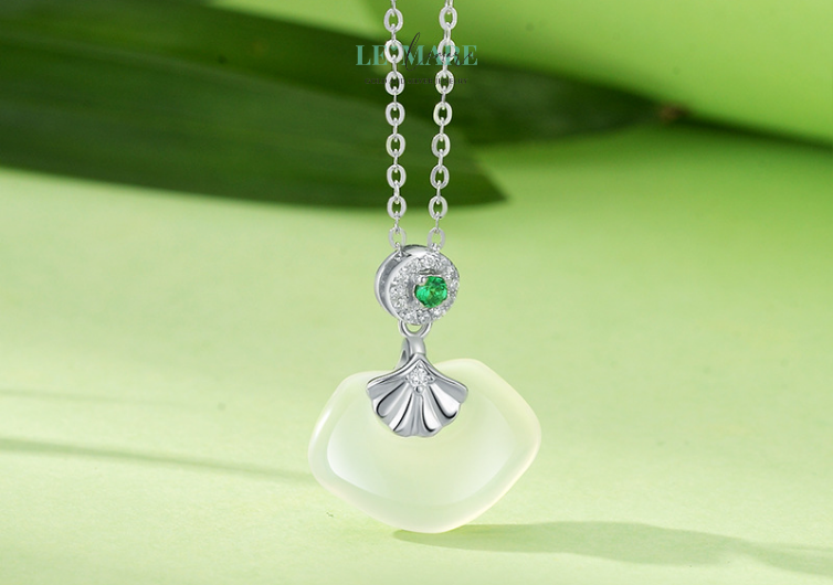 Không lấp lánh như kim cương, không kiêu sa như hồng ngọc, ngọc bích lặng lẽ tỏa sáng theo cách riêng: thâm trầm, dịu mát, như một dòng suối bình yên chảy giữa lòng đá. Qua hàng triệu năm, viên ngọc được chắt lọc từ tinh khí núi rừng đã trở thành bảo vật trong văn hóa phương Đông, tượng trưng cho sự an nhiên, thuần khiết và trường tồn.Trong “Ngọc Phiến”, viên ngọc ấy được đặt giữa lòng một chiếc quạt tay cách điệu – nhẹ nhàng, uyển chuyển – như một nàng thiếu nữ e ấp sau vành quạt, ánh mắt khẽ nghiêng, giấu nửa nụ cười quyền lực.